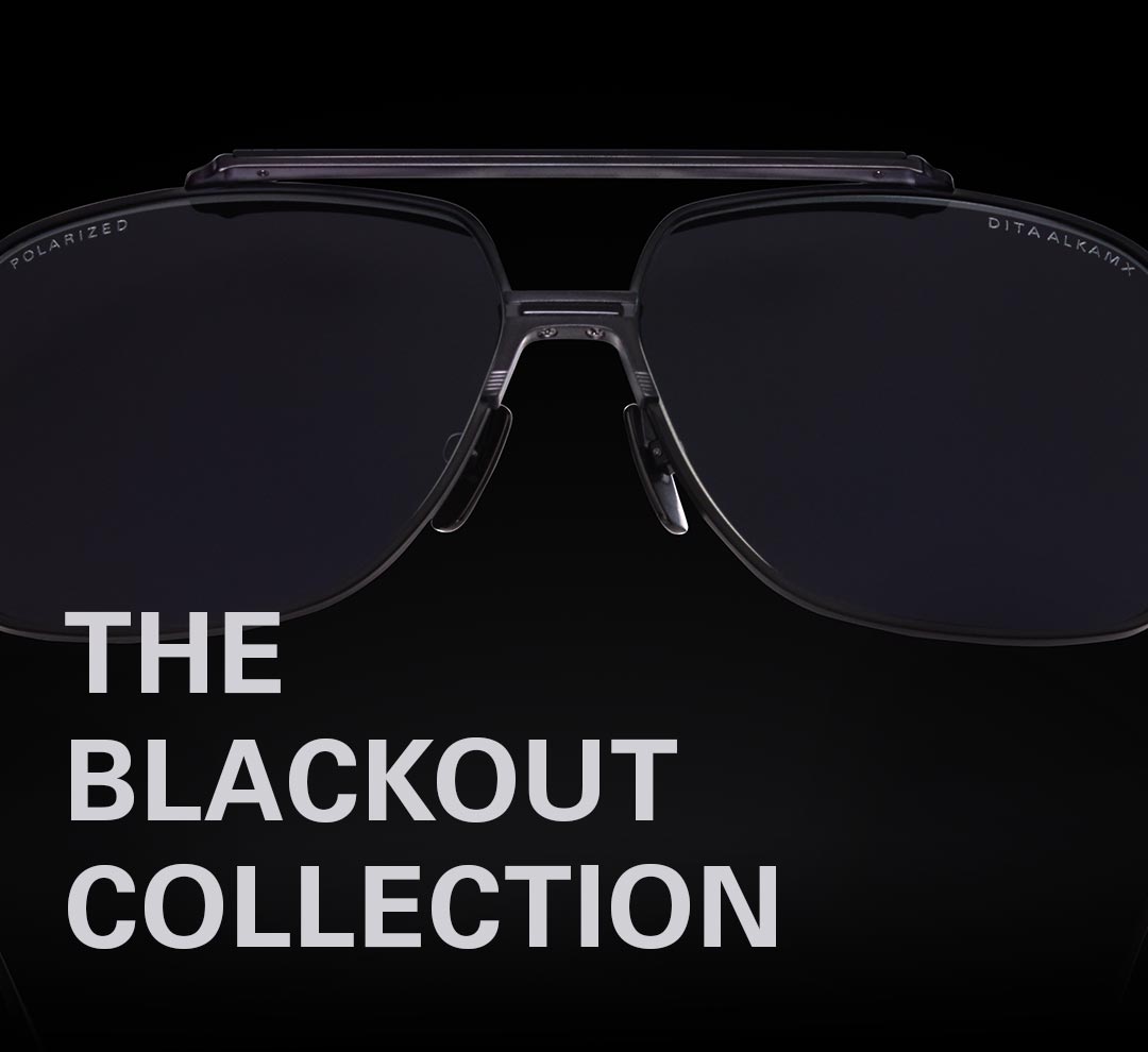 Close-up of sleek black aviator sunglasses with reflective dark lenses on a black background. Text reads "The Blackout Collection," conveying elegance.