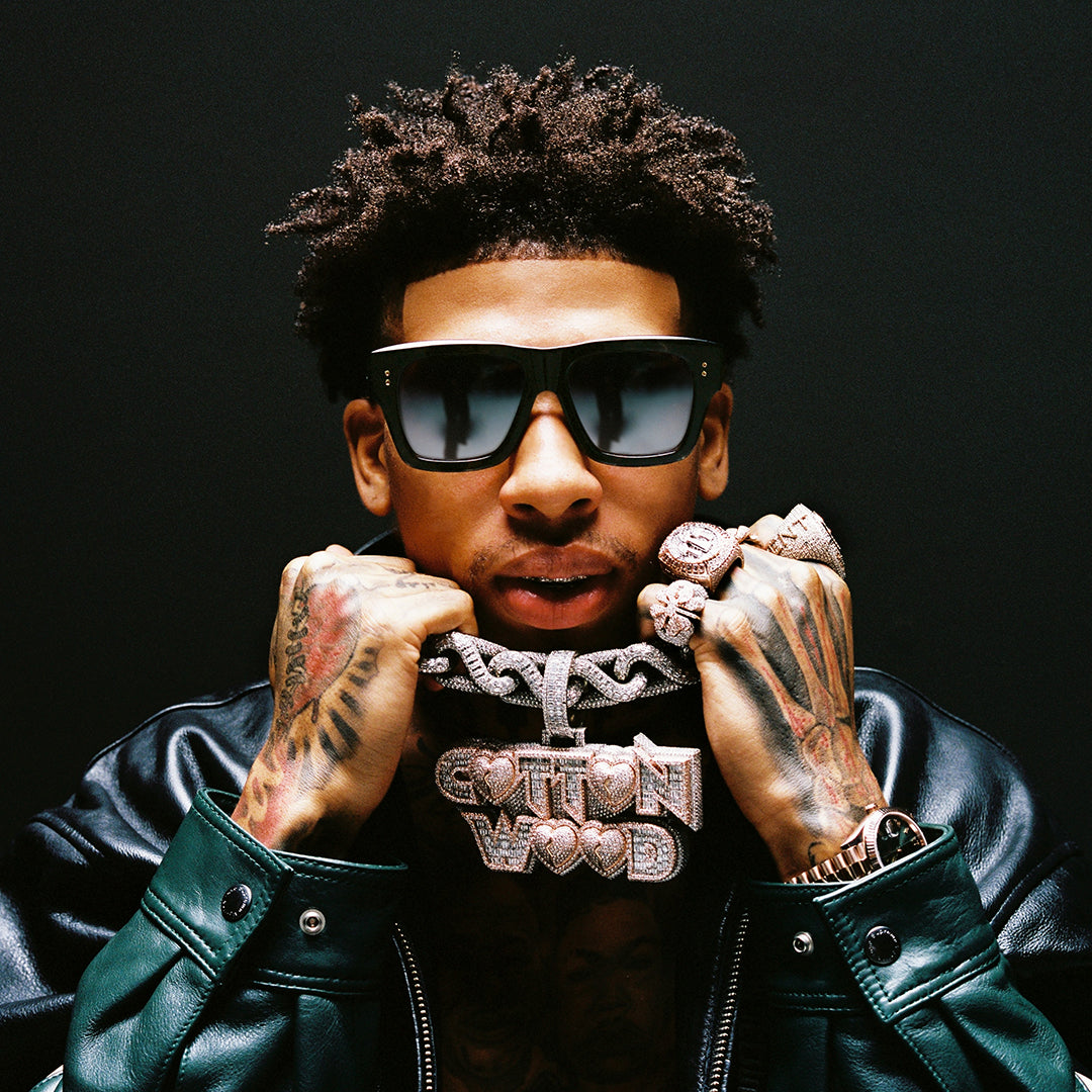 A person wearing sunglasses and a black leather jacket holds a large diamond-studded chain reading "COTTONWOOD." The mood is bold and confident.