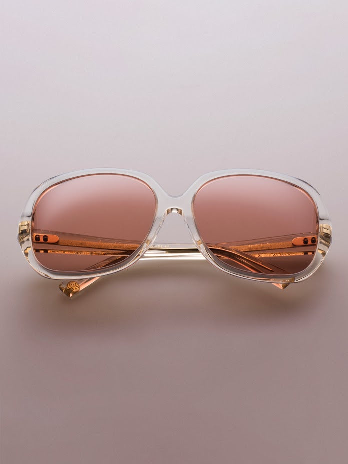 Stylish sunglasses with transparent frames and rose-tinted lenses placed on a soft gradient background, conveying a modern and elegant tone.