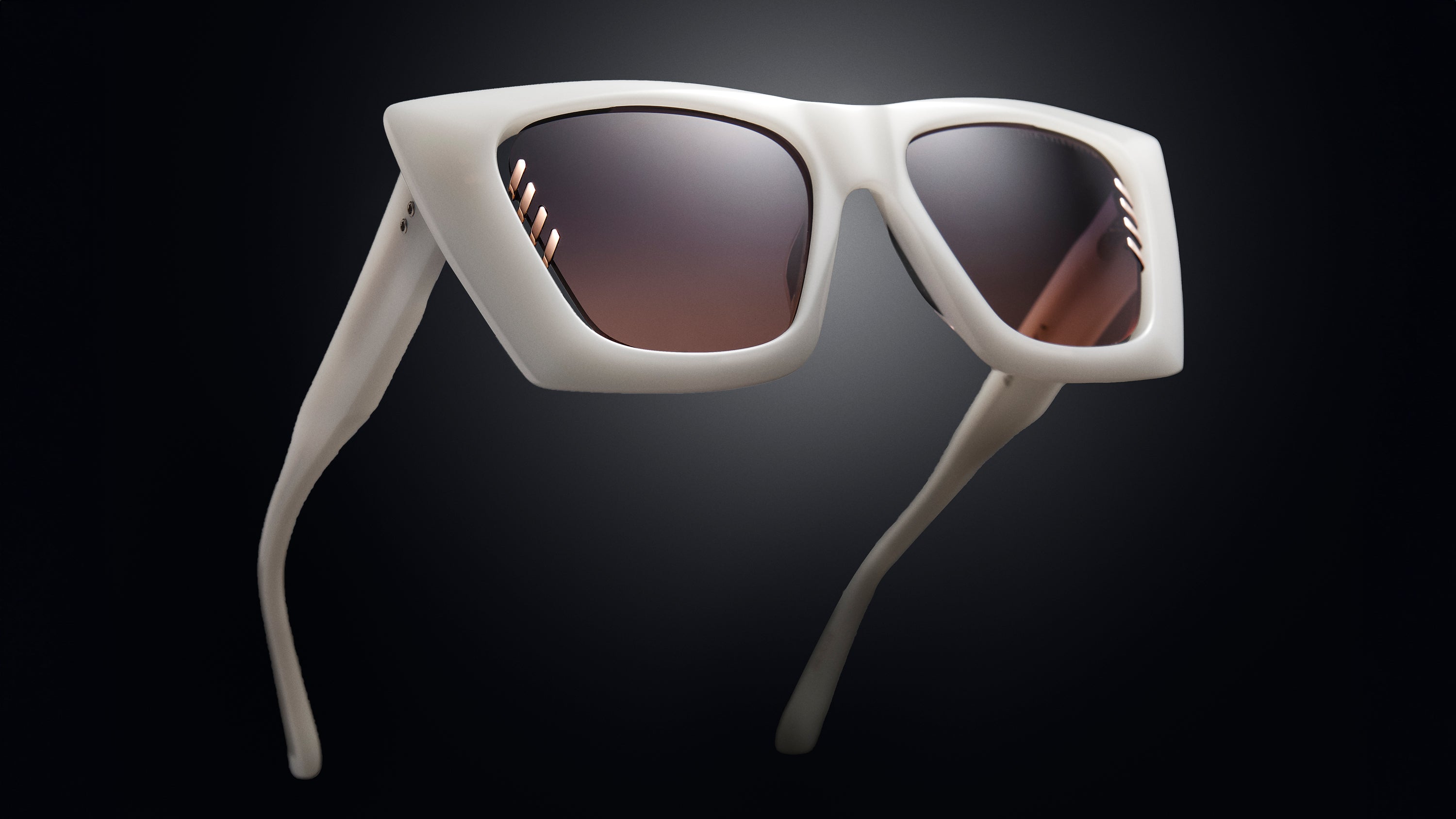 White sunglasses with dark lenses on a black background