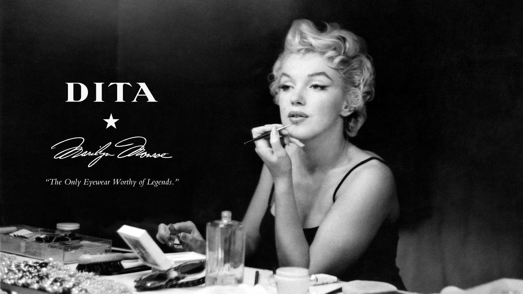 In a classic black-and-white photo, Marilyn Monroe elegantly applies makeup at a vanity. The ad features DITA eyewear with a quote: The Only Eyewear Worthy of Legends.